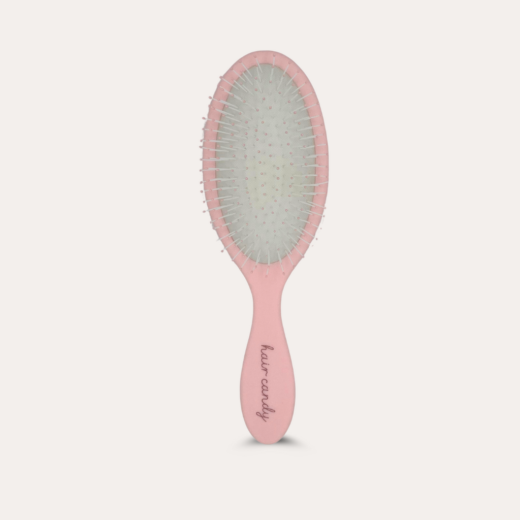 Pink hairbrush with bristle head on a light gray background