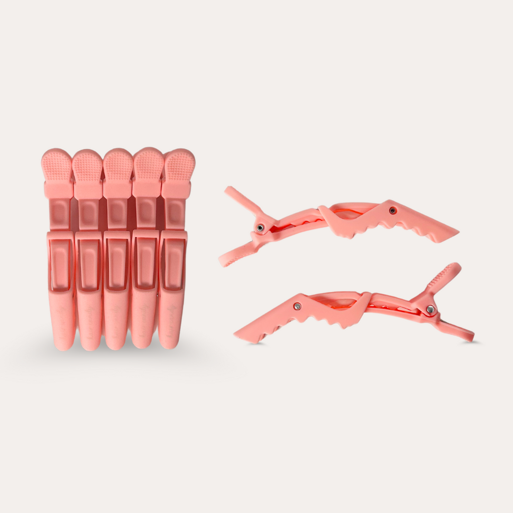 A set of five pink alligator hair clips with serrated edges, displayed alongside and separate from each other against a white background.