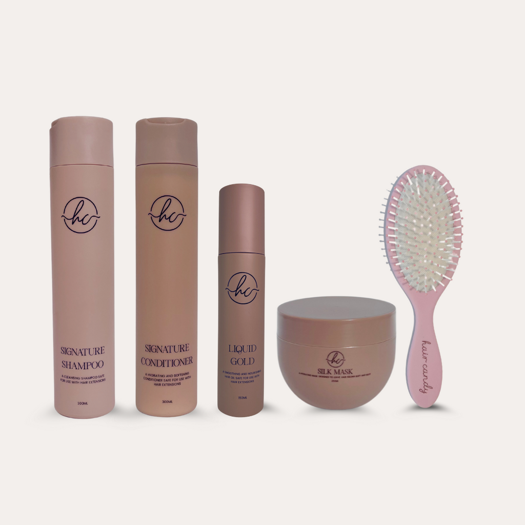 A set of hair care products including shampoo, conditioner, hair oil, silk mask, and a brush, all presented in pink packaging.