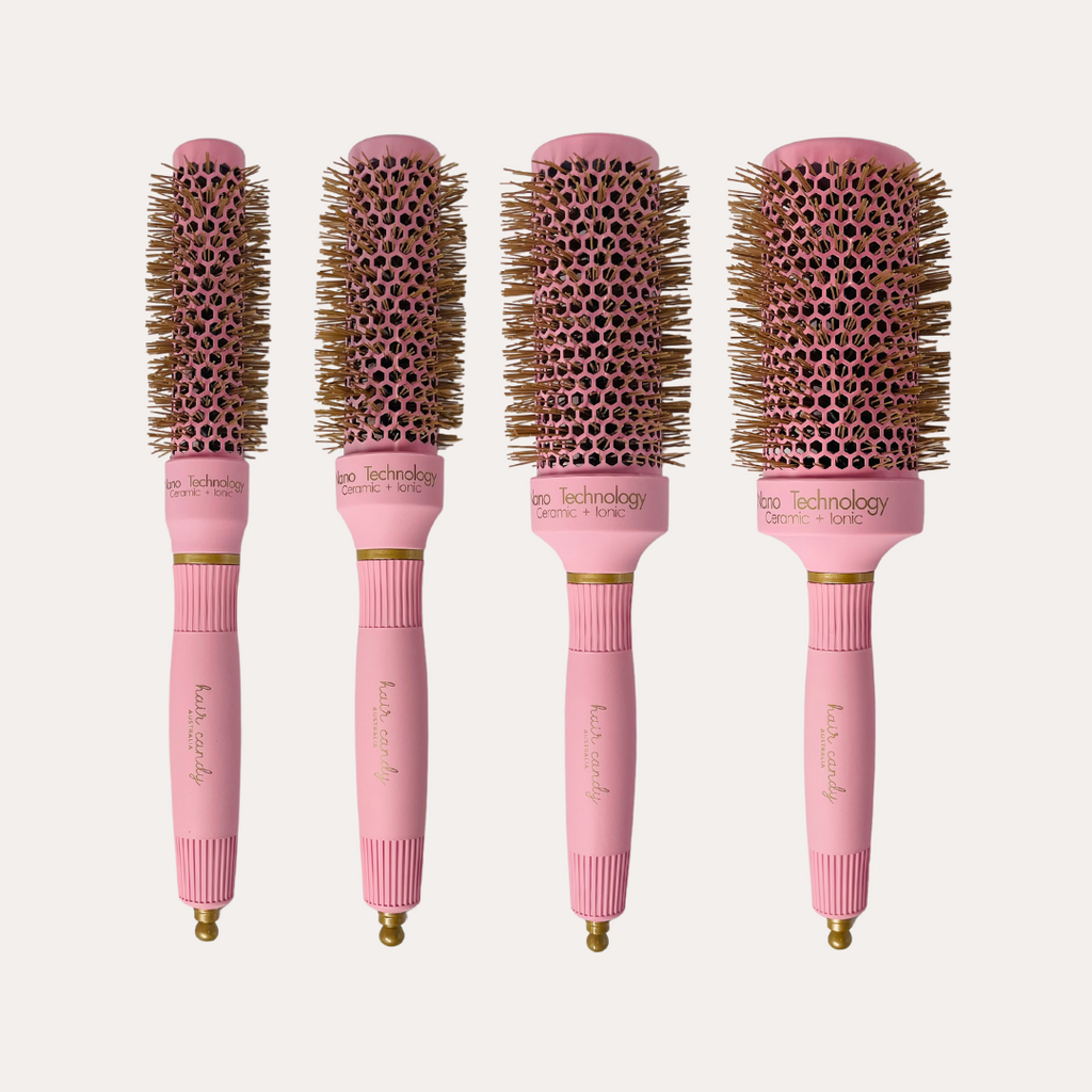 A set of four pink hair round brushes with gold bristles, displayed in varying sizes.