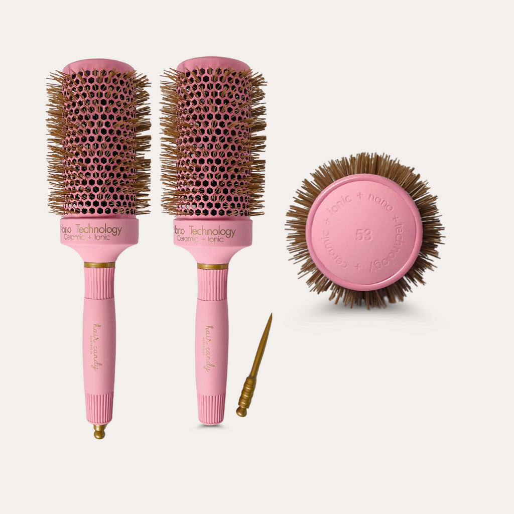 A set of two pink hair brushes with gold bristles, a round shape, and a gold sectioning pin.