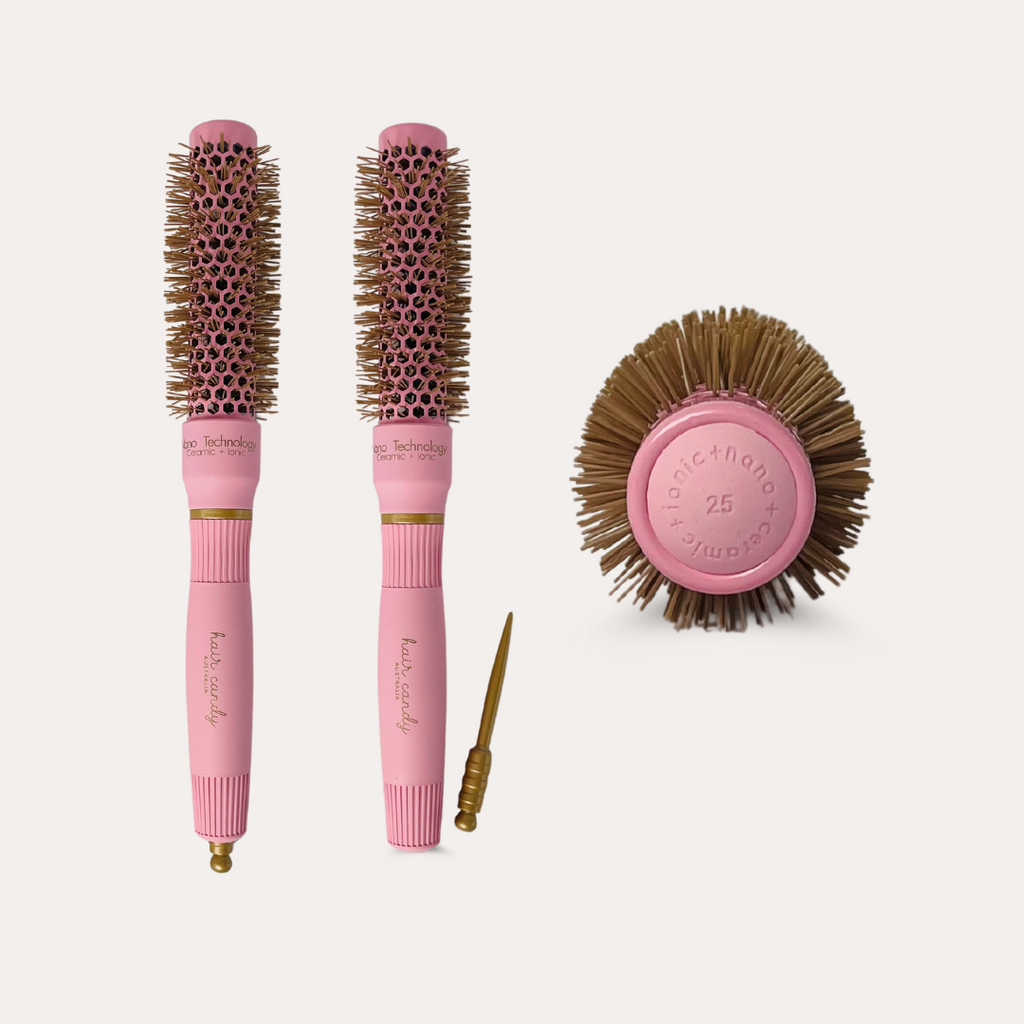 A set of two pink hair brushes with gold bristles, a round brush, and a gold sectioning pin, all with the brand name 'Hair Candy' written on them.