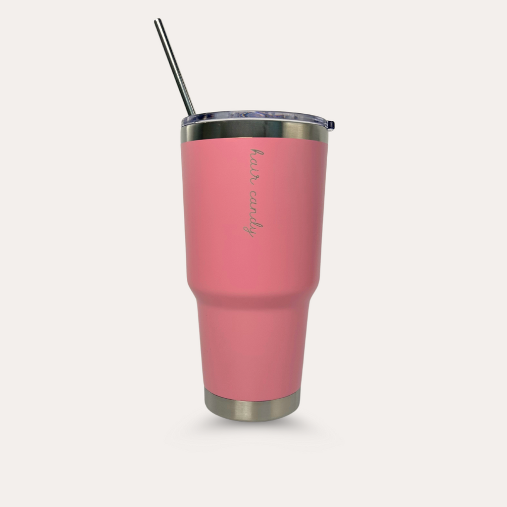 A pink insulated travel mug with a metal straw, featuring the brand logo 'Hair Candy' on the side.