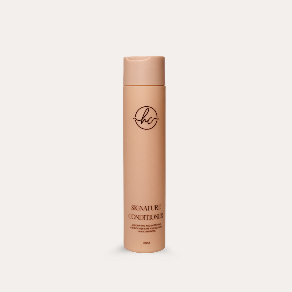 Beige conditioner bottle with HC logo on a light beige background