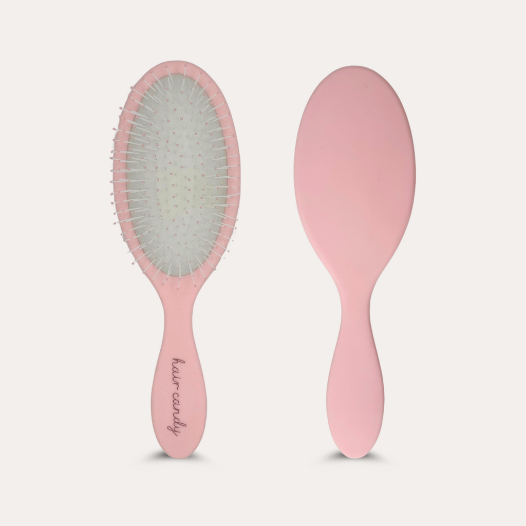 Pink hairbrush with bristle head and smooth handle on a light gray background